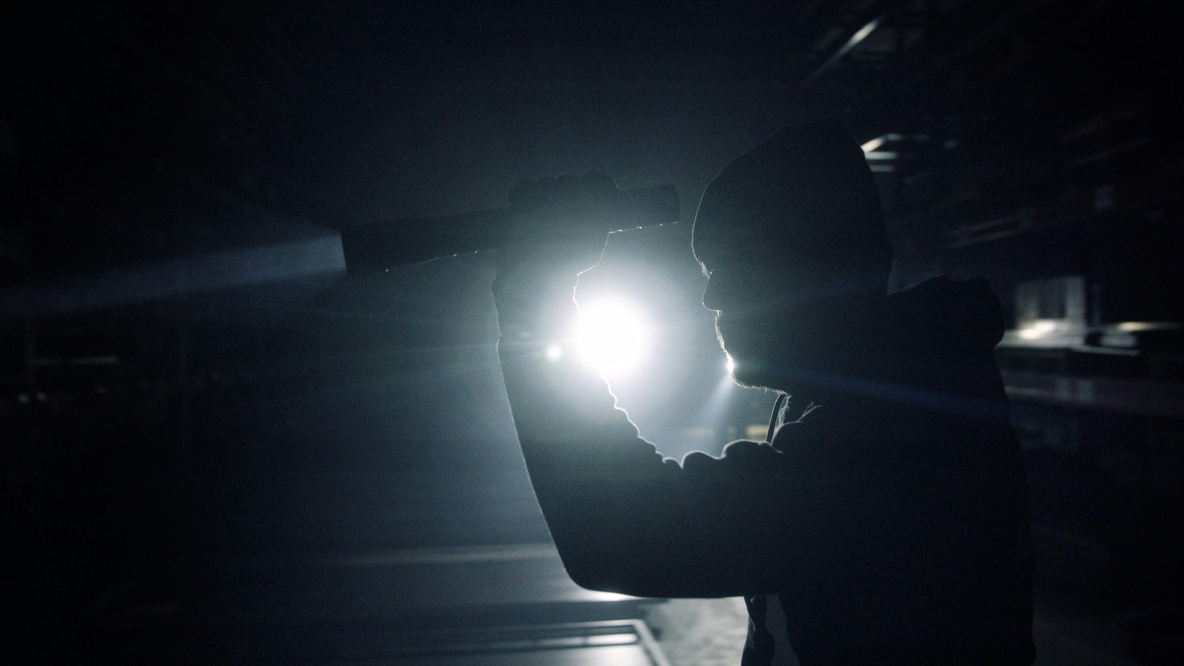 Ein Einbrecher leuchtet mit der Taschenlampe durch eine Fabrikhalle