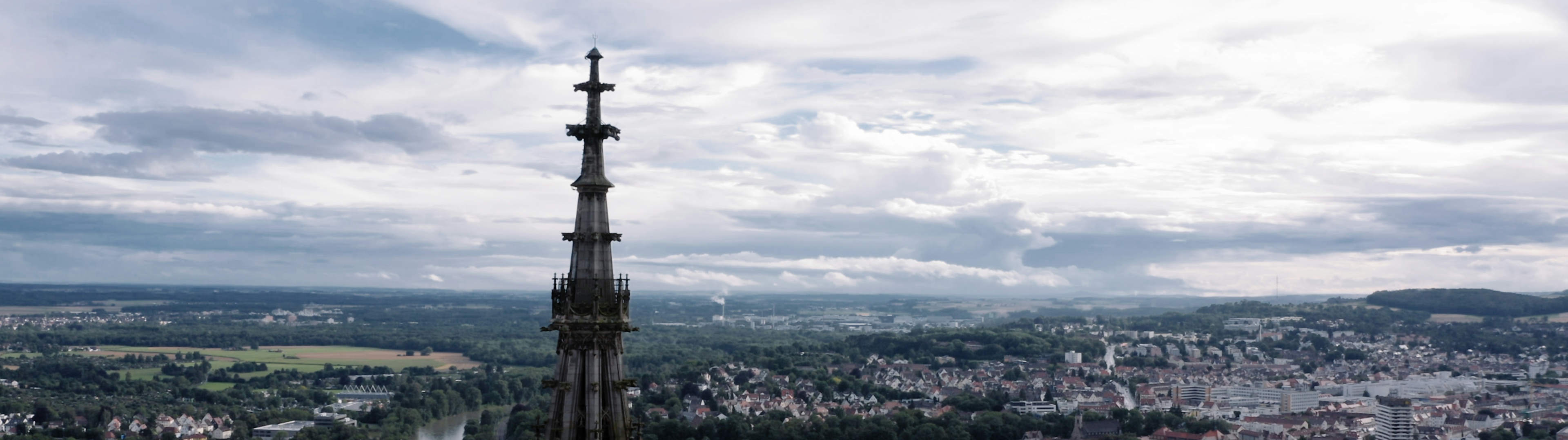 Spitze des Ulmer Münsters vor Landschaft und Himmel