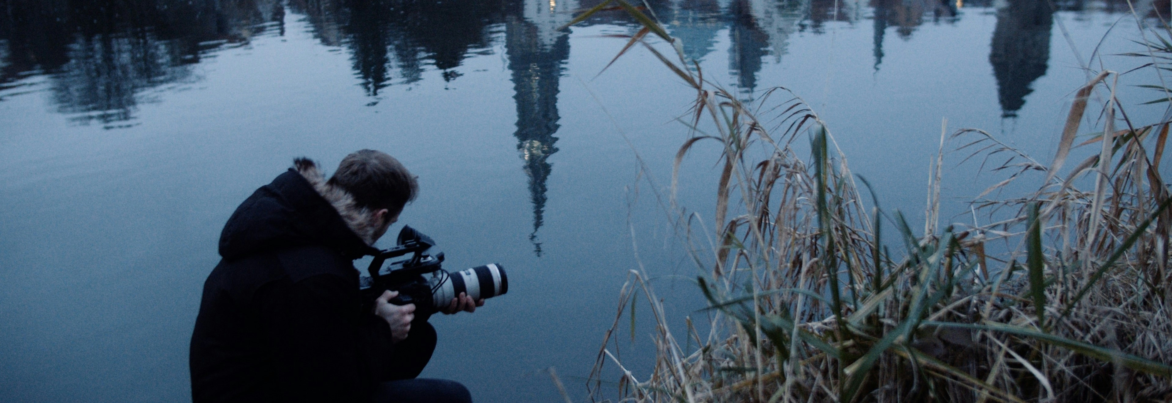 Filmemacher Cornelius Bierer mit Kamera nahe der Donau in dem sich das Ulmer Münster spiegelt